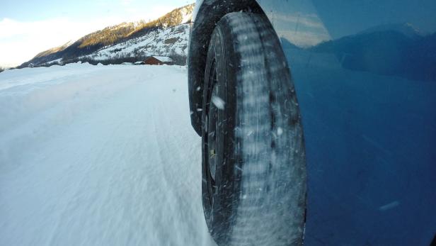 Ein Auto fährt auf einer schneebedeckten Straße in den Bergen.