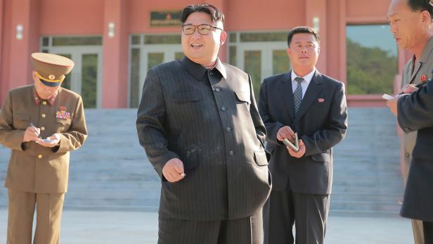Kim Jong-un mit Entourage vor einem Gebäude.