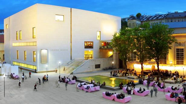 Das Leopold Museum in Wien mit Menschen auf pinkfarbenen Sofas vor dem Gebäude.