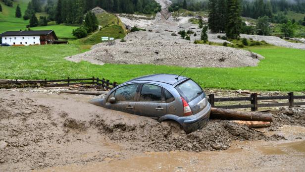 Ein blaues Auto steckt nach einem Erdrutsch im Schlamm fest.