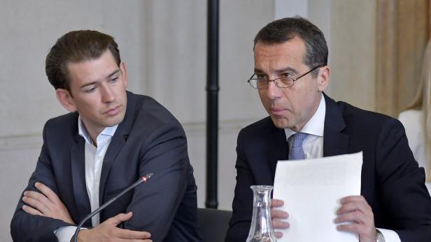 Zwei Männer in Anzügen sitzen an einem Tisch während einer Konferenz.