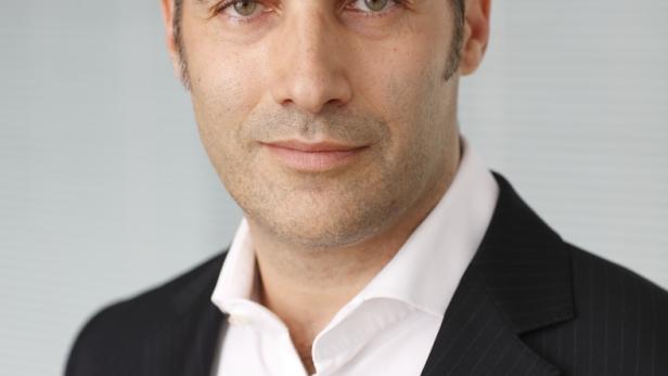 Ein Mann mit dunklen Haaren und Anzug blickt in die Kamera.