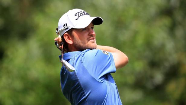 Ein Golfspieler schwingt seinen Schläger vor einem grünen Hintergrund.