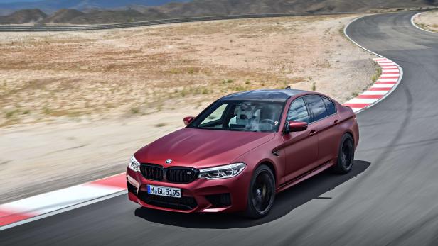 Ein rotbrauner BMW M5 fährt auf einer Rennstrecke.