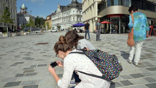 Passanten zücken Handys und fotografieren Reste der Grabstein-Inschriften