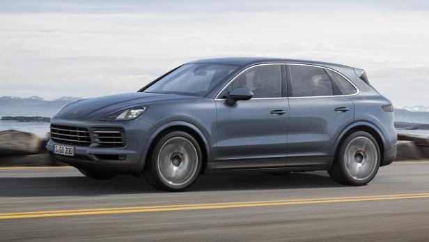 Ein grauer Porsche Cayenne fährt auf einer Küstenstraße.