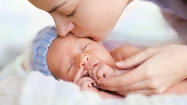 Close up of sleeping newborn and kissing mother