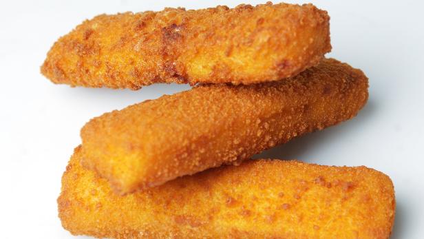 Drei goldbraune Fischstäbchen liegen übereinander.