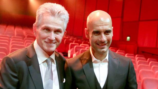 Matthias Sammer und Pep Guardiola posieren vor roten Sitzen.