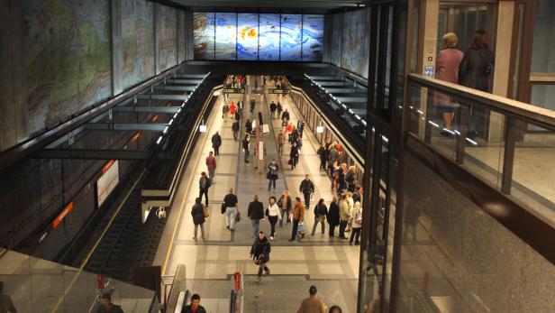Blick auf einen belebten U-Bahnhof mit wartenden und umsteigenden Menschen.