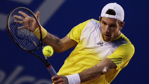 Ein Tennisspieler schlägt einen Ball mit seinem Schläger.