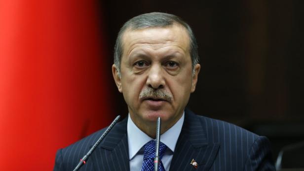 Recep Tayyip Erdoğan spricht vor einem roten Hintergrund in ein Mikrofon.