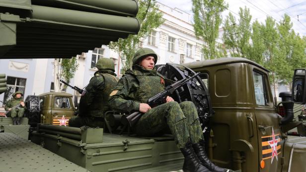 Zwei Soldaten, die auf einem Kriegs-Fahrzeug sitzen