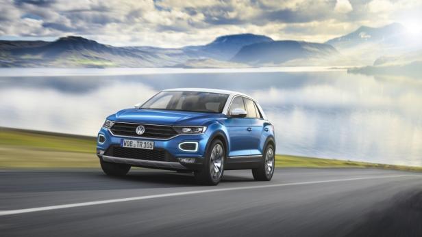 Ein blauer VW T-Roc fährt auf einer Straße vor einer Bergkulisse.