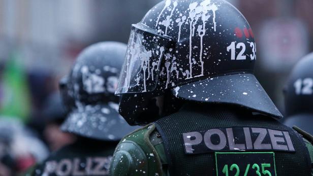 Polizisten in Schutzausrüstung, deren Helme mit Farbe beschmiert sind.