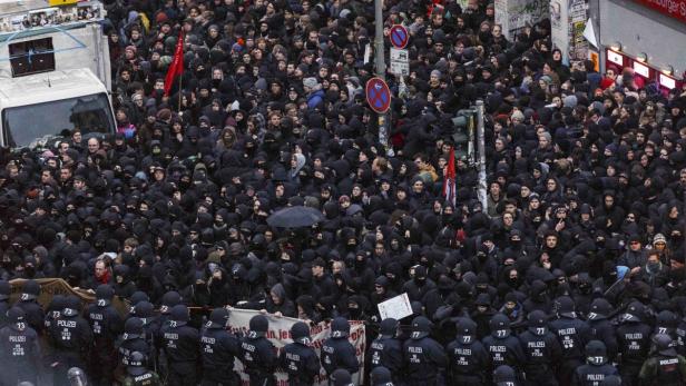 Eine große Menschenmenge demonstriert, bewacht von einer Reihe Polizisten.