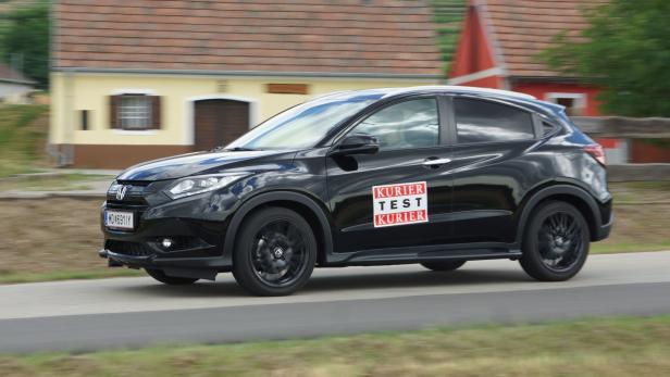 Ein schwarzer Honda HR-V mit „Kurier Test Kurier“-Aufklebern fährt auf einer Straße.