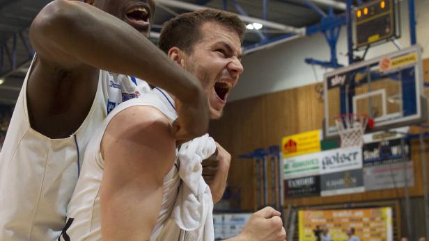 Zwei Basketballspieler jubeln auf dem Spielfeld über einen Sieg.