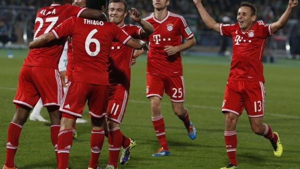Fußballspieler des FC Bayern München feiern auf dem Rasen.