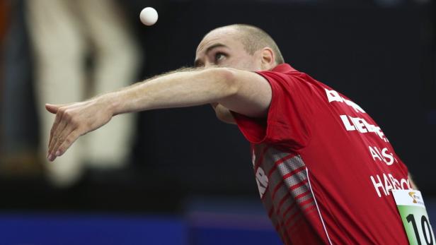Ein Tischtennisspieler schlägt den Ball beim Aufschlag.