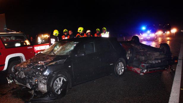 Ein schwerer Autounfall mit Feuerwehrleuten am Unfallort bei Nacht.