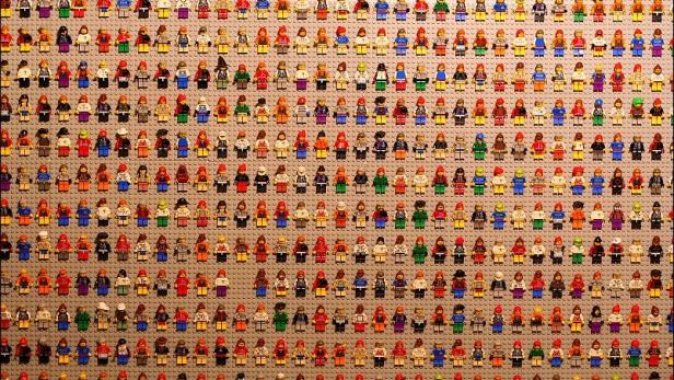 Eine große Sammlung von Lego-Figuren auf einer grauen Grundplatte.