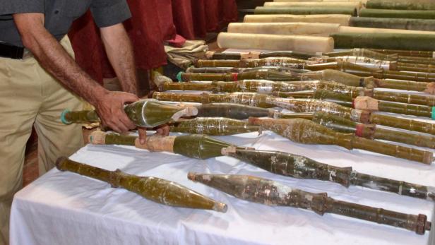 Ein Mann hantiert mit einer Sammlung von Panzerfäusten auf einem Tisch.