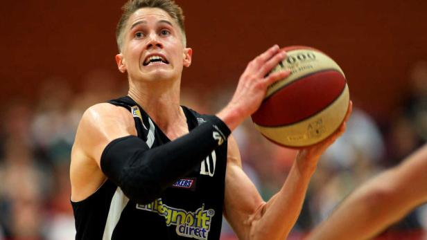Ein Basketballspieler mit angespanntem Gesichtsausdruck hält einen Ball.