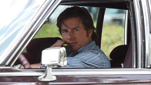 Tom Cruise sitzt in einem älteren Cadillac und spricht in ein Funkgerät.