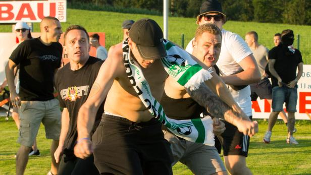 Eine Gruppe von Fußballfans steht auf einem Rasenplatz.