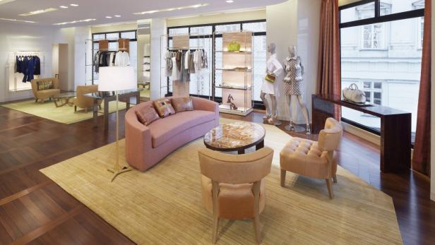 Innenansicht eines Bekleidungsgeschäfts mit Sitzbereich und Auslagen.