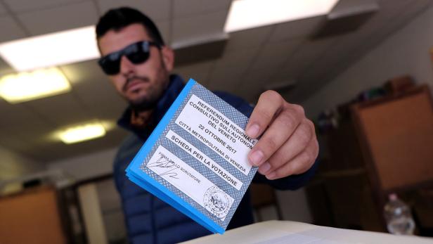 Ein Mann hält einen Stimmzettel für das Regionalreferendum in Venetien 2017 in der Hand.