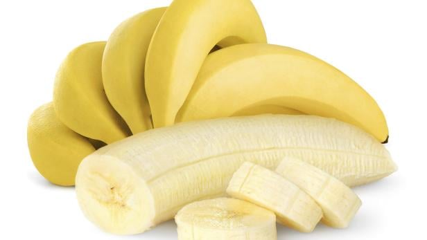 Eine geschälte, aufgeschnittene Banane vor einem Bündel gelber Bananen