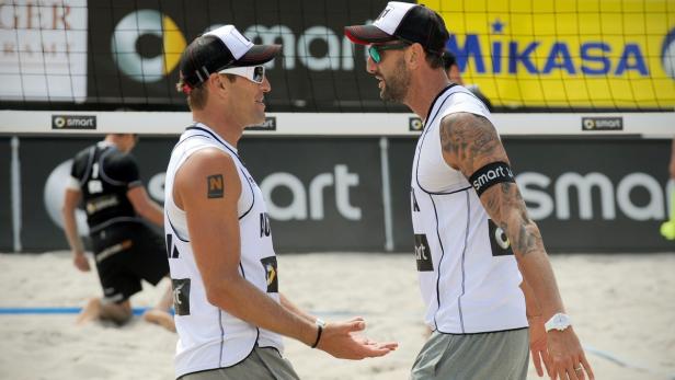 Zwei Beachvolleyballspieler unterhalten sich am Netz.