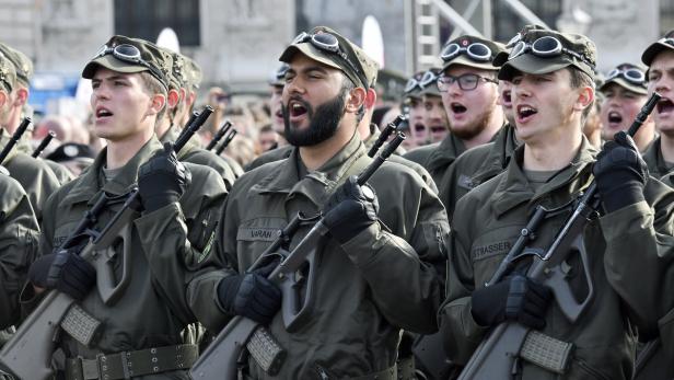In einer Reihe aufgestellte Männer in Uniform mit Kappen und Gewehren