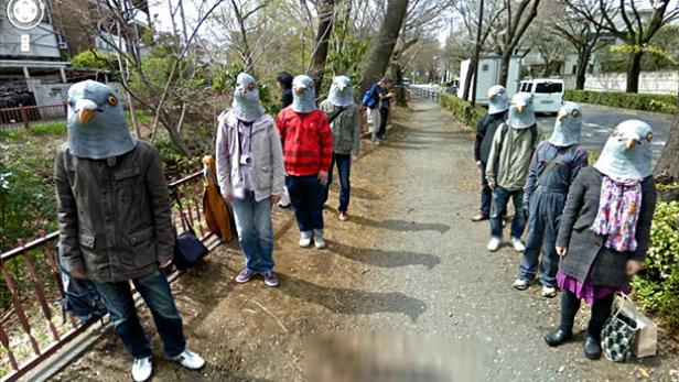 Eine Gruppe von Menschen mit Taubenkopfmasken steht am Straßenrand.