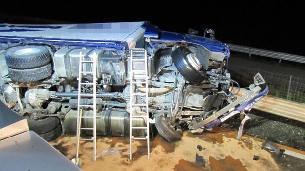 Ein umgekippter blauer Lastwagen liegt auf der Seite, eine Leiter steht daneben.