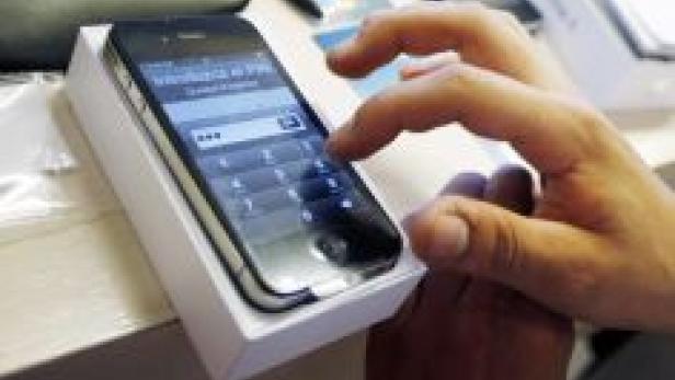 Eine Person tippt auf dem Bildschirm eines Smartphones, das in seiner Verpackung liegt.