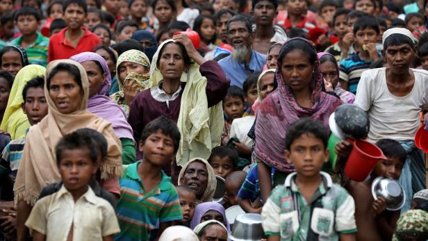 Rohingya refugees wait outside of an aid distribut
