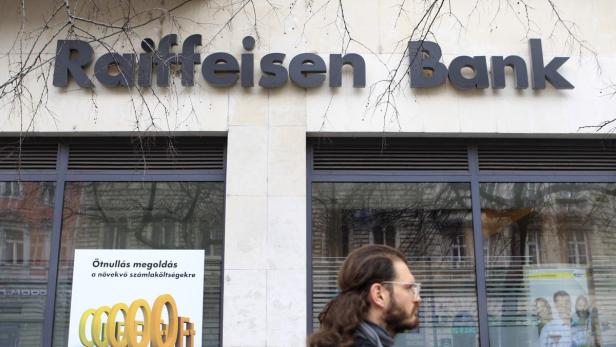 Eine Filiale der Raiffeisen Bank mit einem Passanten im Vordergrund.