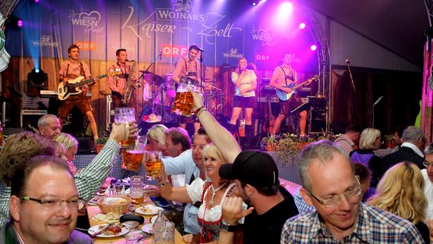Besucher prosten einer Band im Festzelt auf dem Wiener Wiesn-Fest zu.