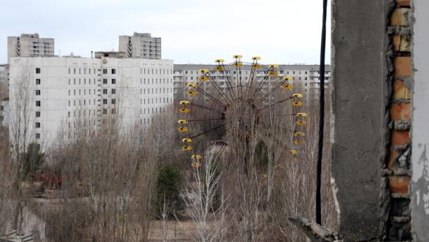 Ein verlassenes Riesenrad in Prypjat, Ukraine, mit Wohnblöcken im Hintergrund.