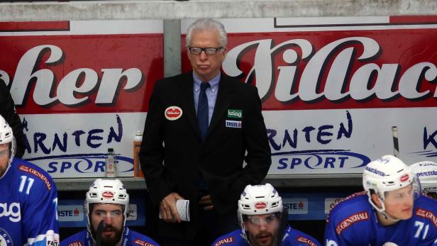 Ein Trainer steht vor der Spielerbank des Villacher SV Eishockeyteams.