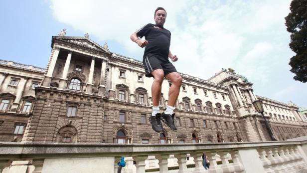 Ein Mann springt vor der Hofburg in Wien in die Luft.