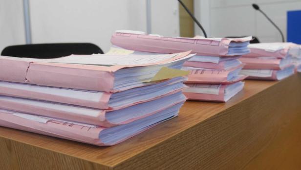 Mehrere Aktenordner liegen auf einem Schreibtisch.