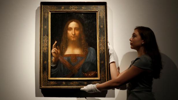 Members of Christie&#039;s staff pose for pictures next to Leonardo da Vinci&#039;s &quot;Salvator Mundi&quot; painting which will be auctioned by Christie&#039;s in New York in November, in London, Britain October 24, 2017. REUTERS/Peter Nicholls NO RESALES. NO ARCHIVES