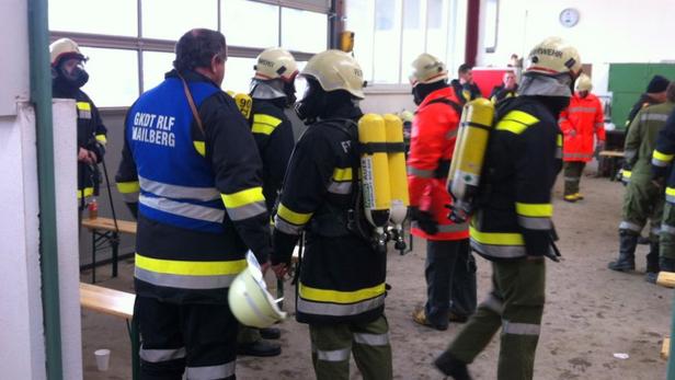 Eine Gruppe Feuerwehrleute mit Atemschutzgeräten in einer Halle.
