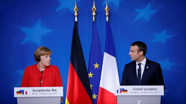 Macron (r.) drängt – aber Merkel hängt bei ihrer Regierungsbildung.
