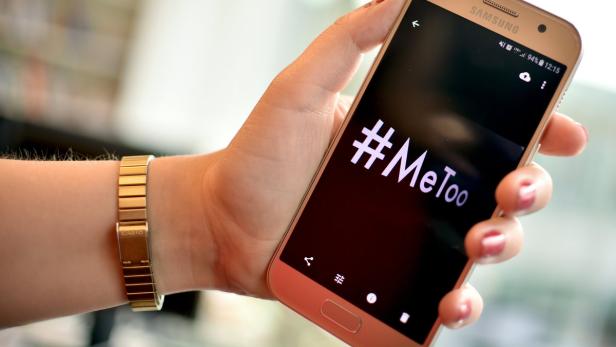 Eine Hand hält ein Smartphone, auf dessen Bildschirm der Hashtag #MeToo zu sehen ist.