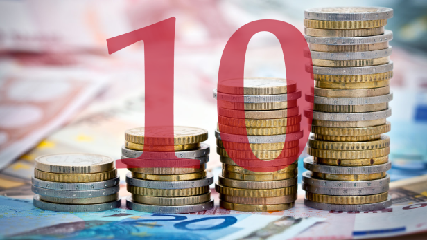 Münzstapel auf Geldscheinen mit einer roten „10“ im Vordergrund.